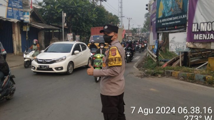 Anggota Bhabinkamtibmas Polsek Rajeg Aipda Rusdi,melaksanakan giat pengaturan lalu lintas untuk kelancaran perjalanan masyarakat bekerja.