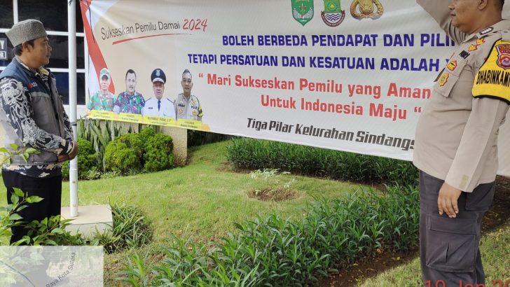 Babinkamtibmas Bripka Abd muzizat melaksanakan pemasangan sepanduk pemilu damai 2024